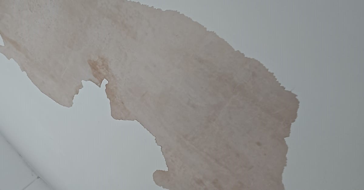 Peeling paint on a bathroom ceiling caused by moisture buildup and poor ventilation.